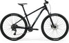 Side view of a black Merida BIG.NINE 300 hardtail mountain bike with front suspension, black frame, and Maxxis tires.