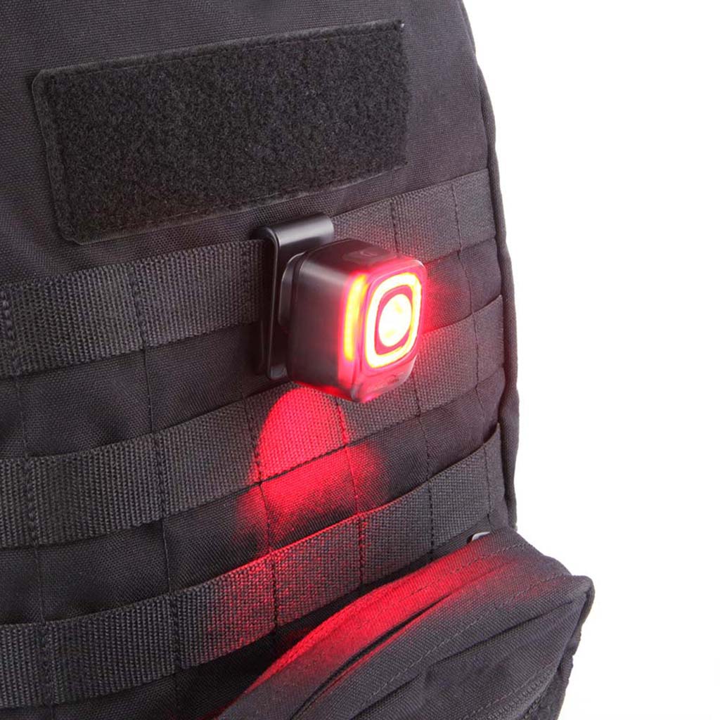 A small black bicycle rear light clipped onto a black saddlebag attached to a bicycle seat.