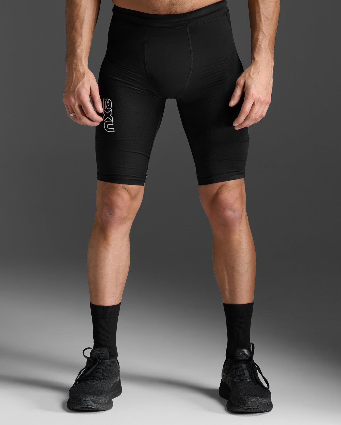 2XU Light Speed React Compression Shorts in Black/White Reflective, front view showing the 2XU thigh logo.