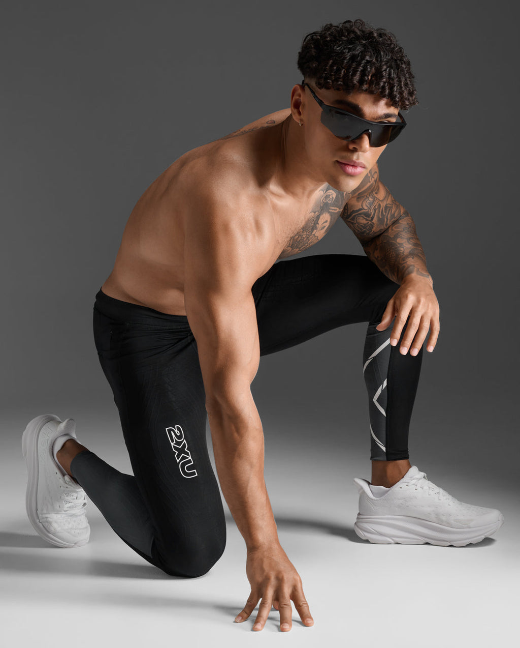 Male athlete wearing the 2XU Light Speed React Compression Tights in a kneeling sprint-start pose.