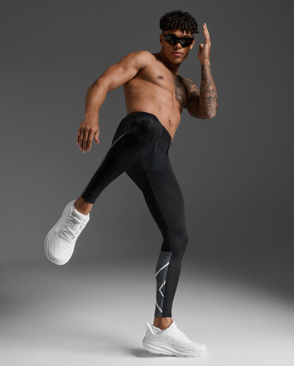 Male athlete in the 2XU Light Speed React Compression Tights performing a dynamic running stride, side hip pocket visible.