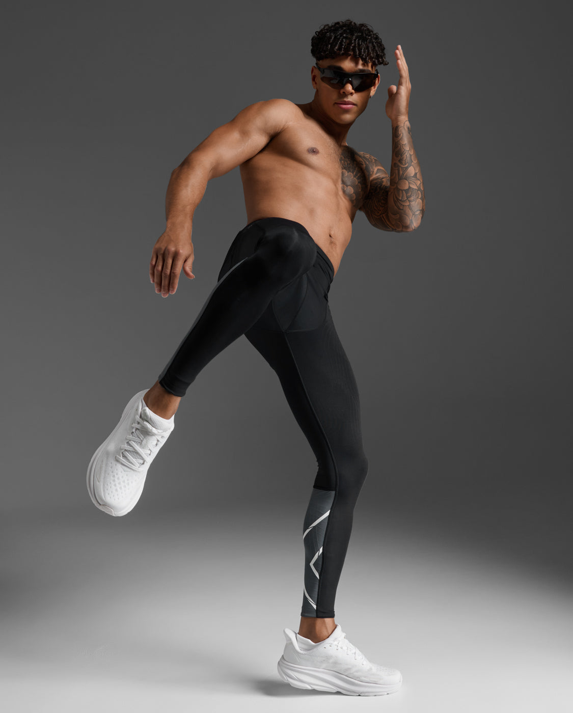 Male athlete in the 2XU Light Speed React Compression Tights performing a dynamic running stride, side hip pocket visible.
