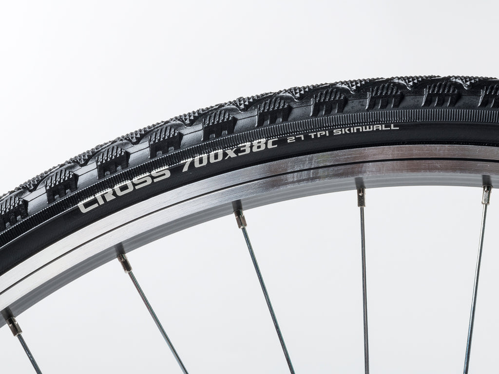 A close-up of a bicycle tire displaying the text "cross 700x32" on its sidewall.
