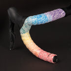 GUEE Attitude Fade Rainbow cycling bar tape with black end-plugs, featuring improved damping for maximum hand comfort and road shock absorption.