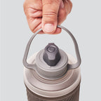 Hydrapak 750ml bottle with bail handle shown on trekking gear setup.

