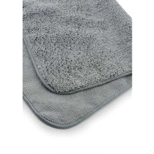 A hand holding the Juice Rag, shown in the process of wiping down and polishing a clean, shiny bicycle frame.