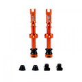 A pair of orange Juice Lubes tubeless valves (65mm) with their caps on, showcasing the vibrant color and sleek design against a clean background.

