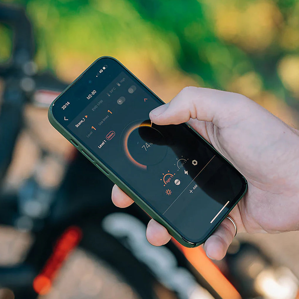 A hand holds a smartphone displaying the Magicshine App, used for customizing the EVO 1700 light.