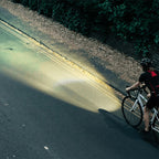  A cyclist rides on a dark road, illuminated by the powerful beam of the Magicshine EVO 1700 front light.