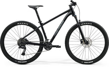 Side view of a black Merida BIG.NINE 300 hardtail mountain bike with front suspension, black frame, and Maxxis tires.

