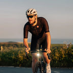 A rider's hands on a bicycle, with the Magicshine EVO 1700SD light shining brightly.