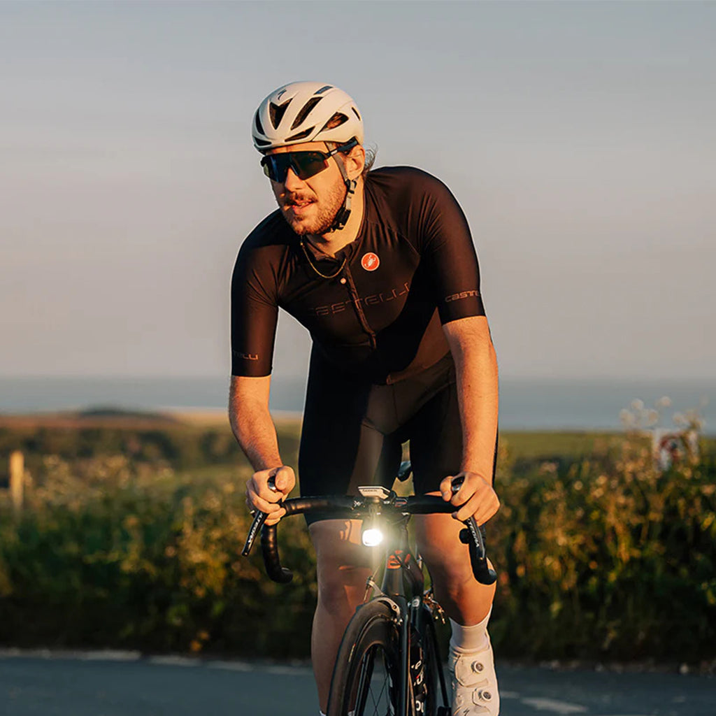 A rider's hands on a bicycle, with the Magicshine EVO 1700SD light shining brightly.