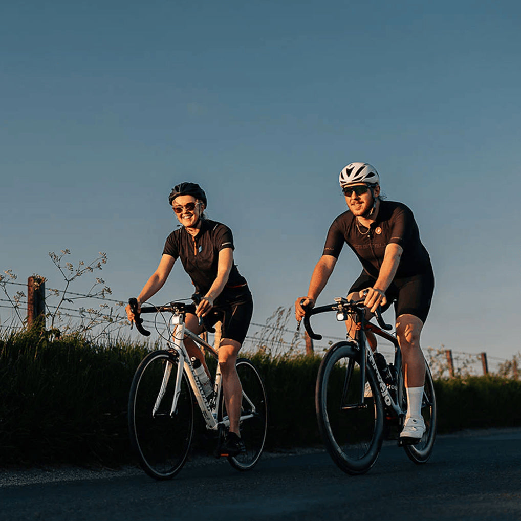 Two cyclists ride together on a sunny road, one bike featuring the Magicshine EVO 1700 light.