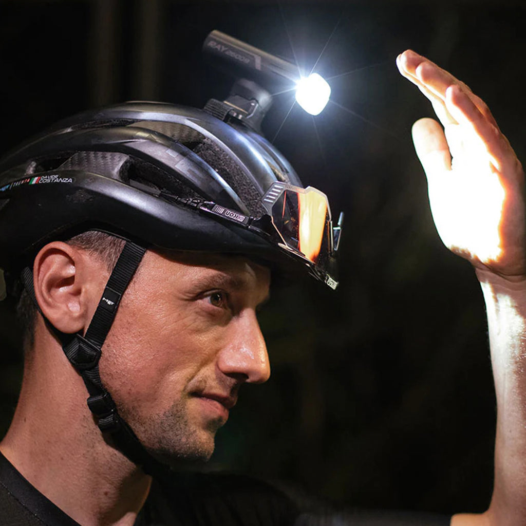 The Magicshine RAY 2600B light is securely mounted on a cycling helmet, demonstrating a versatile attachment option.