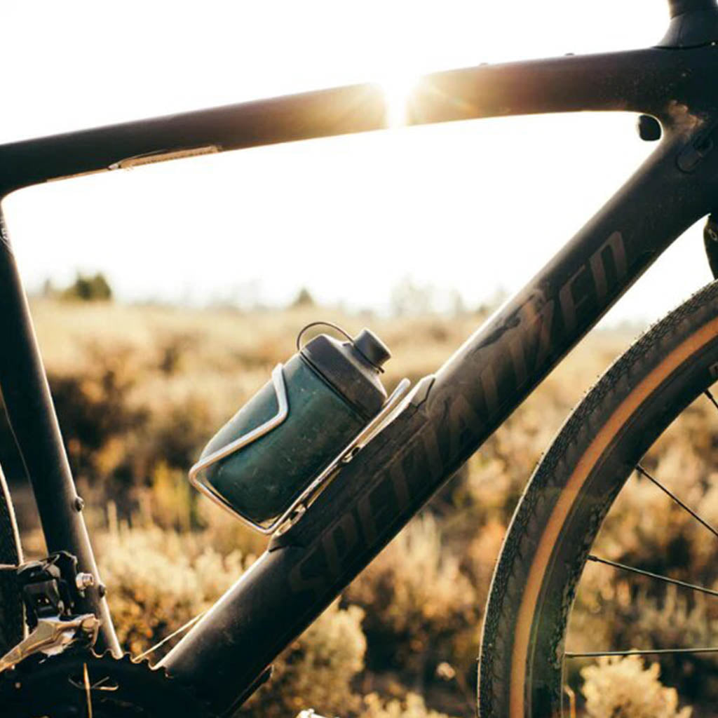 Polar Breakaway Session Muck Bottle (White, 450ml) positioned next to a mountain bike helmet and gloves, representing essential high-quality gear for trail and gravel riding."