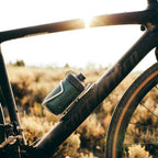 Polar Breakaway Session Muck Bottle (White, 450ml) positioned next to a mountain bike helmet and gloves, representing essential high-quality gear for trail and gravel riding."