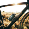 Polar Breakaway Session Muck Bottle (White, 450ml) positioned next to a mountain bike helmet and gloves, representing essential high-quality gear for trail and gravel riding."