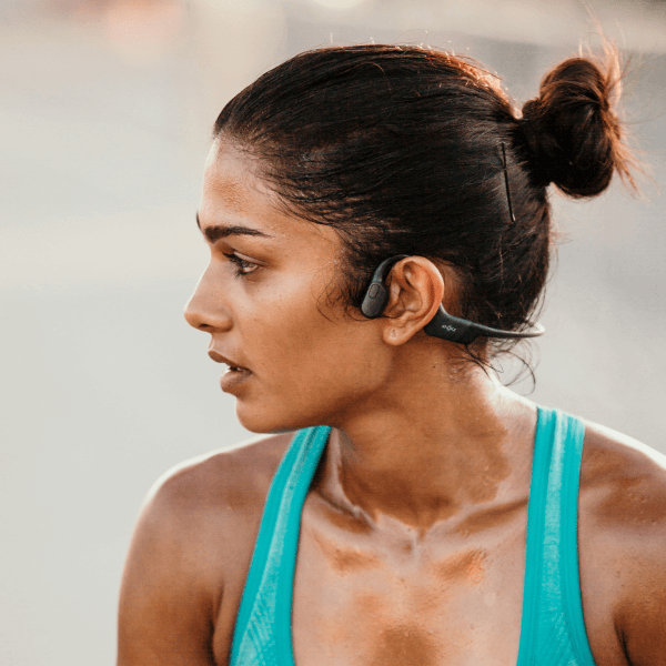 Runner wearing Shokz OpenRun Black bone conduction headphones outdoors.