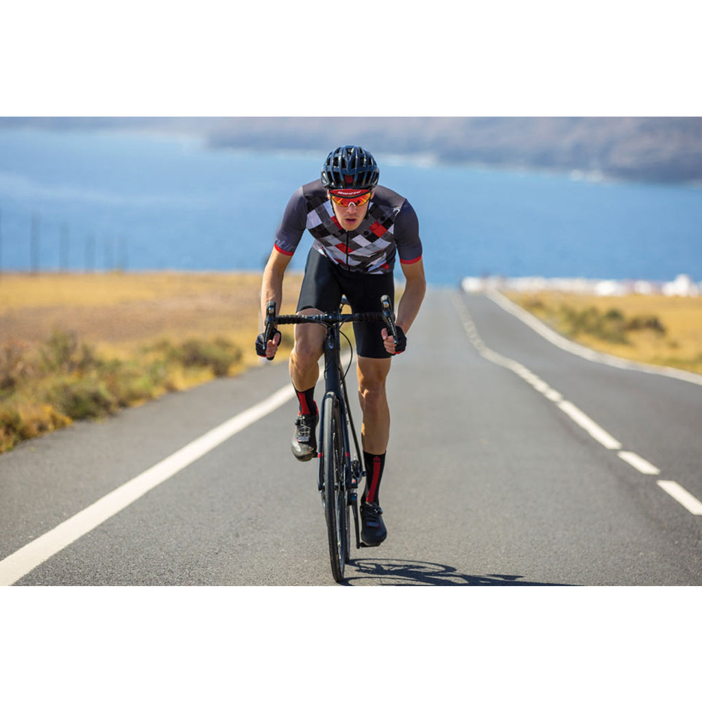 Cyclist wearing the Santini VIS jersey while riding, emphasizing the sleek, race-ready fit, high-performance materials, and reflective elements for safer training sessions.