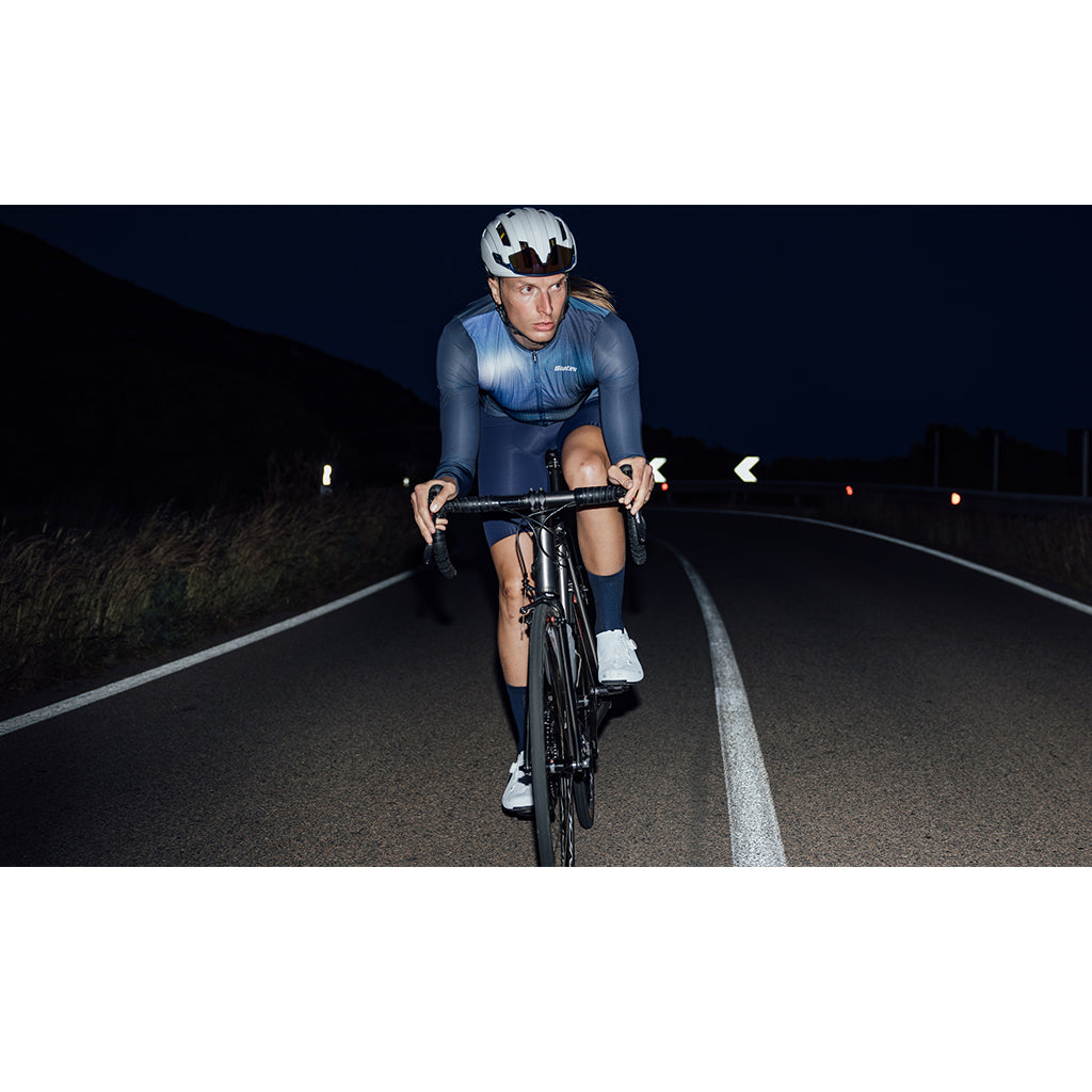 Santini Ombra Eco Sleek Long Sleeve Unisex Jersey in blue, worn by a cyclist in an aggressive riding position, showcasing its aerodynamic fit and full arm sun protection for performance rides.