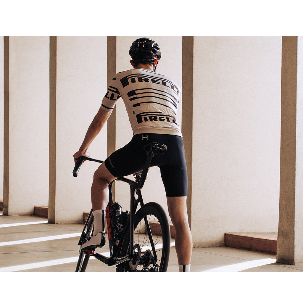 Cyclist wearing the Santini Pirelli Sport Club unisex beige jersey, showcasing its UPF30+ protection and raw-cut sleeves.

