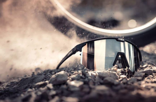  A pair of Bliz Hero Black Sport sunglasses resting on the ground, showcasing their sleek design and sporty style