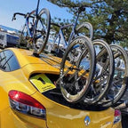 A yellow car showcasing three bikes on its roof, all fastened with a TREEFROG L3 front wheel holder.