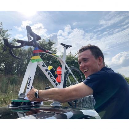A man holds a bike atop a car, showcasing the TreeFrog Pro 1 Bike Rack designed for road and mountain bikes.