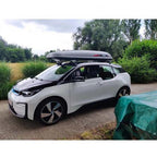 A stylish BMW i3 equipped with a black Treefrog roof rack crossbar, perfect for carrying gear on the go.