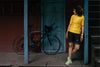 A women staring at her cycle and wearing yellow cycling jersey