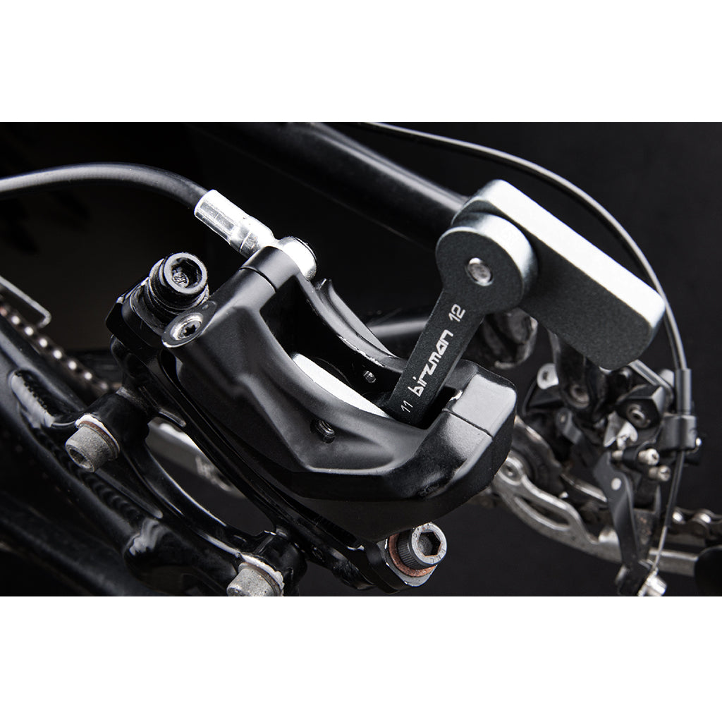 Close-up of the Birzman Piston Release Tool holding back three brake pistons during servicing.