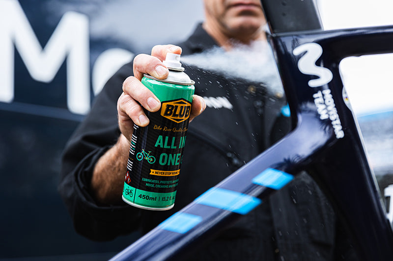 Mechanic applying Blub All in One spray lubricant to a professional road bike frame.