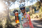 Cyclist spraying Blub Bike Cleaner from the 1L bottle in a forest trail setting.
