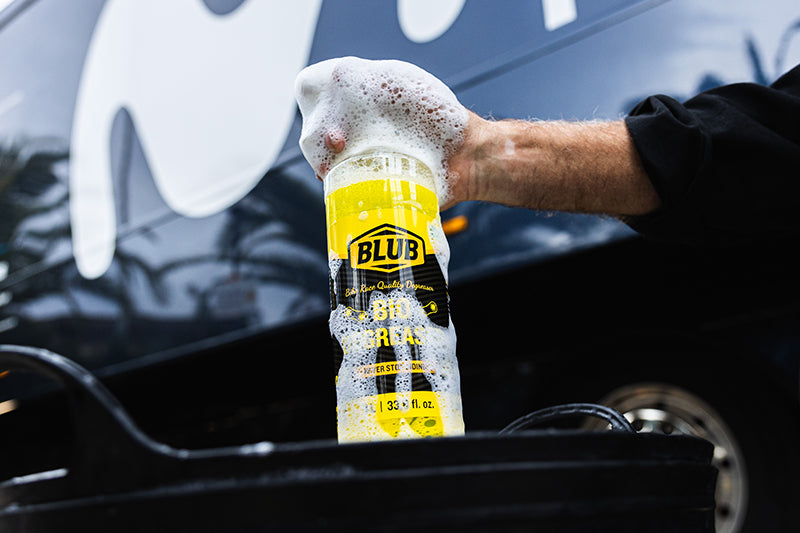 Hand spraying Blub Bio Degreaser foam from the 1L bottle onto a bicycle drivetrain.