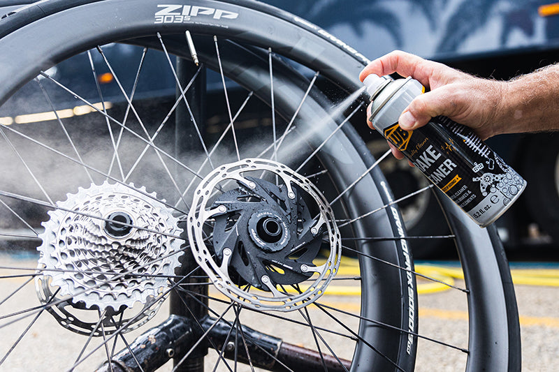 Blub Brake Cleaner being sprayed onto a bicycle wheel's disc brake rotor and cassette during cleaning.