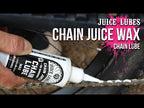 Juice Lubes Chain Juice Wax (130ml), shown being applied to a bike chain, indicating its use for a clean and efficient drivetrain.

