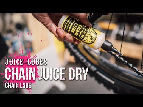 Juice Lubes Chain Lube - Dry Condition Chain Oil (130ml), shown being applied to a bike chain, indicating its use for optimal performance in arid conditions.

