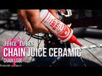 Juice Lubes Chain Juice - Ceramic High Performance Chain Oil (130ml), shown being applied to a bike chain, indicating its premium use for demanding cycling conditions.

