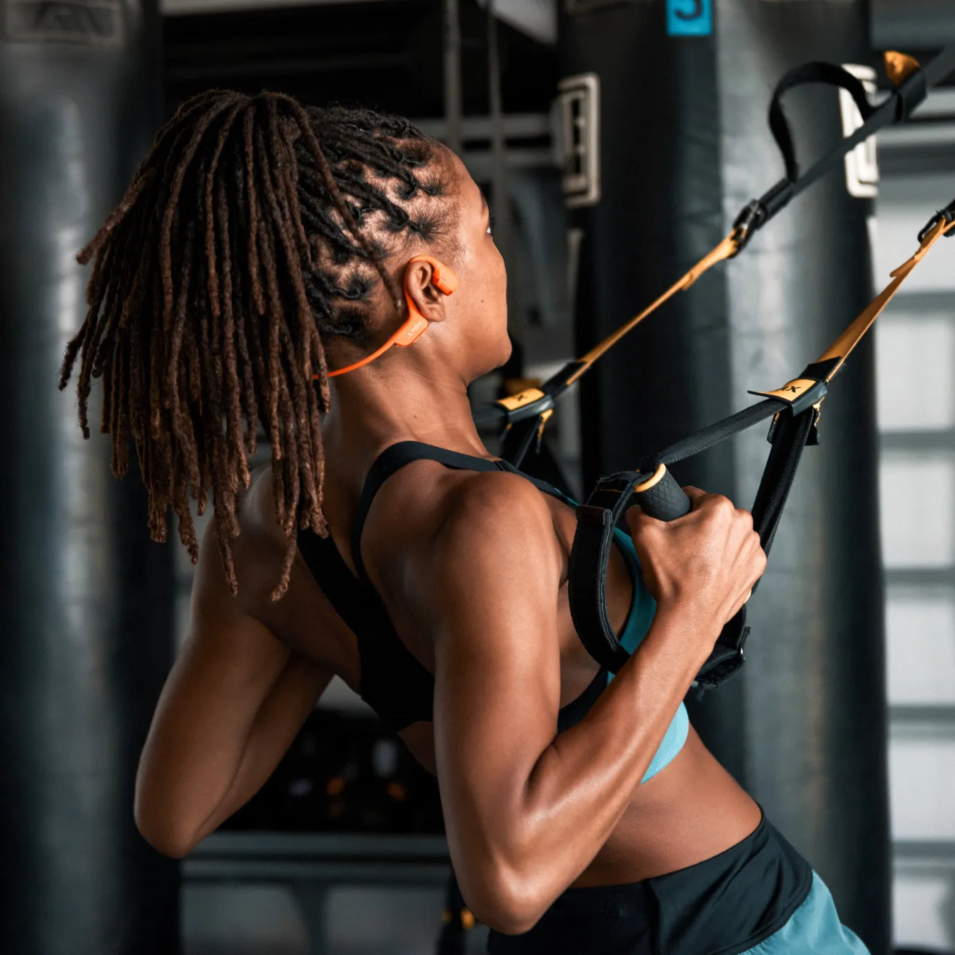 Runner wearing Shokz OpenRun Pro 2 orange headphones outdoors during a winter training session.