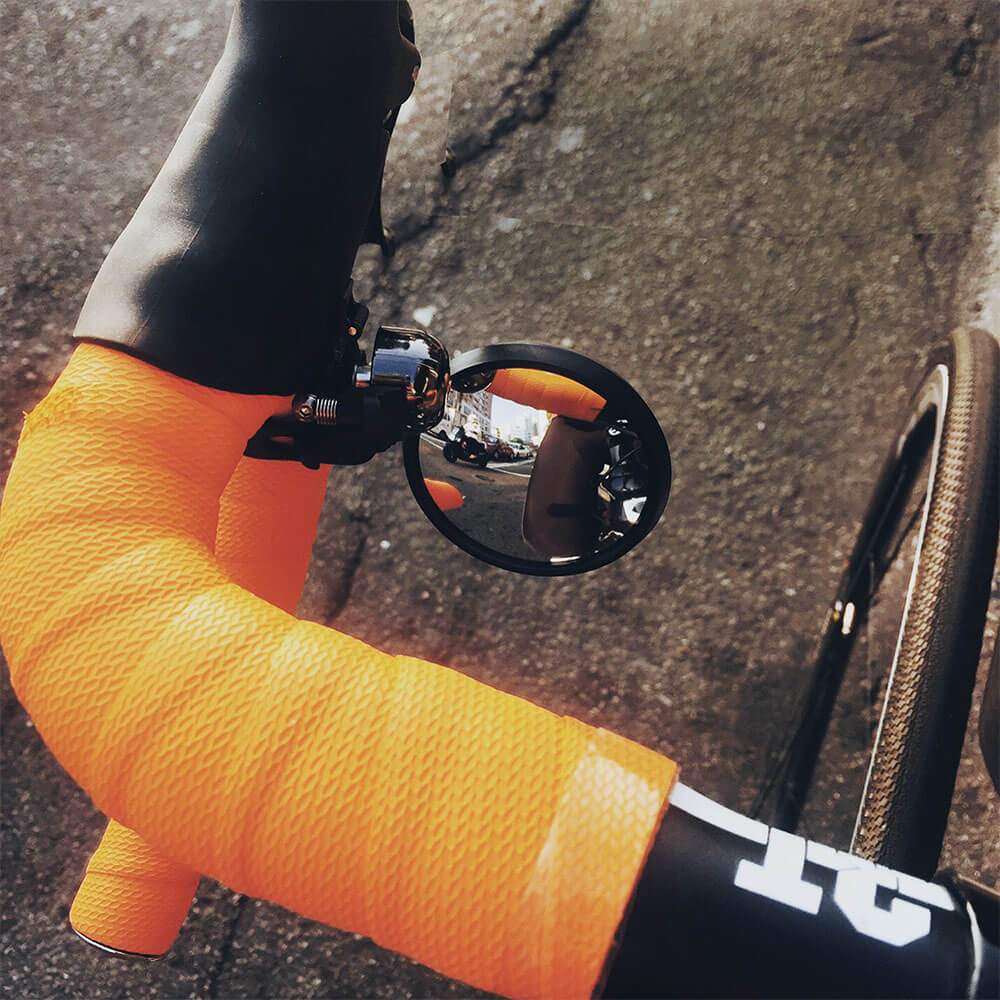 An image of the Guee i-See Safety Bike Mirror from a rider's perspective, demonstrating its 360° horizontal and +/-20° angle adjustment. 
